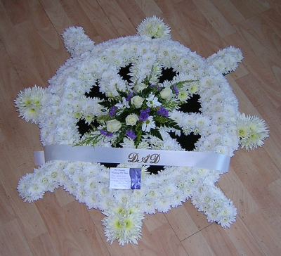 Ships wheel - A personal tribute in shape of ships wheel, massed in white chrysanthemums with a contrasting spray of customer choice flowers.